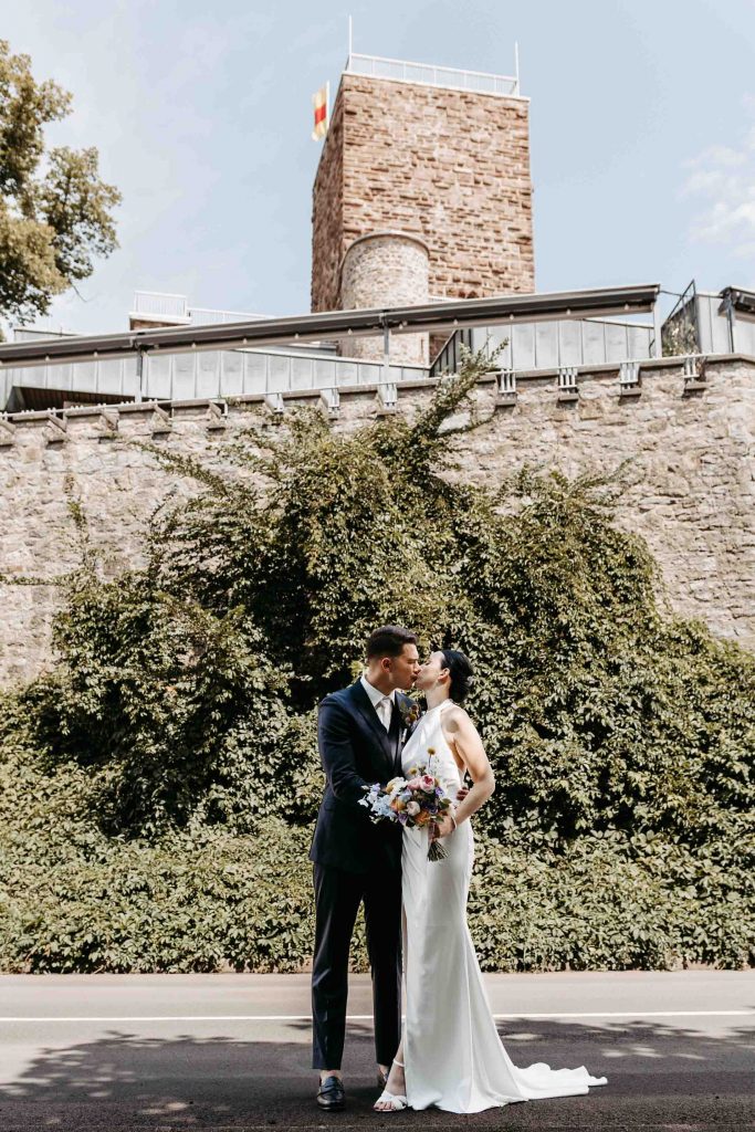 Brautpaar küsst sich. Im Hintergrund sieht man den Turm auf dem Turmberg.