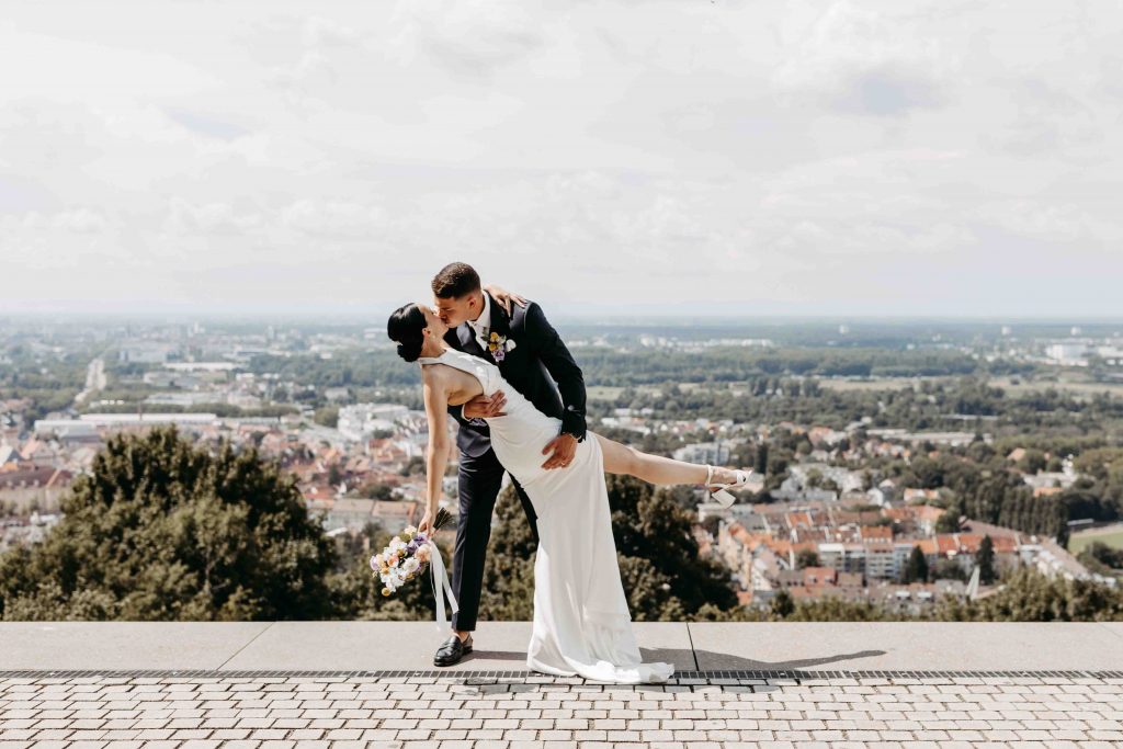 Brautpaar küsst sich wie in Hollywood. das Brautpaar steht mittig umgeben von einem Panoramablick über Karlsruhe.