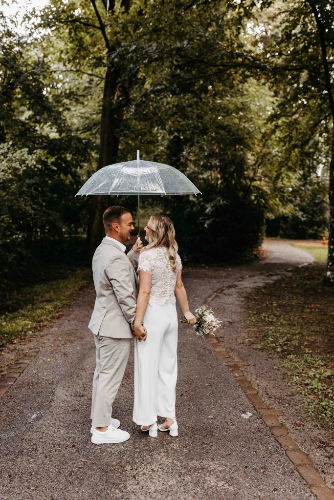 Es nieselt. Im Park auf dem Turmberg in Karlsruhe steht das Brautpaar unter einem Schirm und schaut sich an. Die beiden halten Händchen.