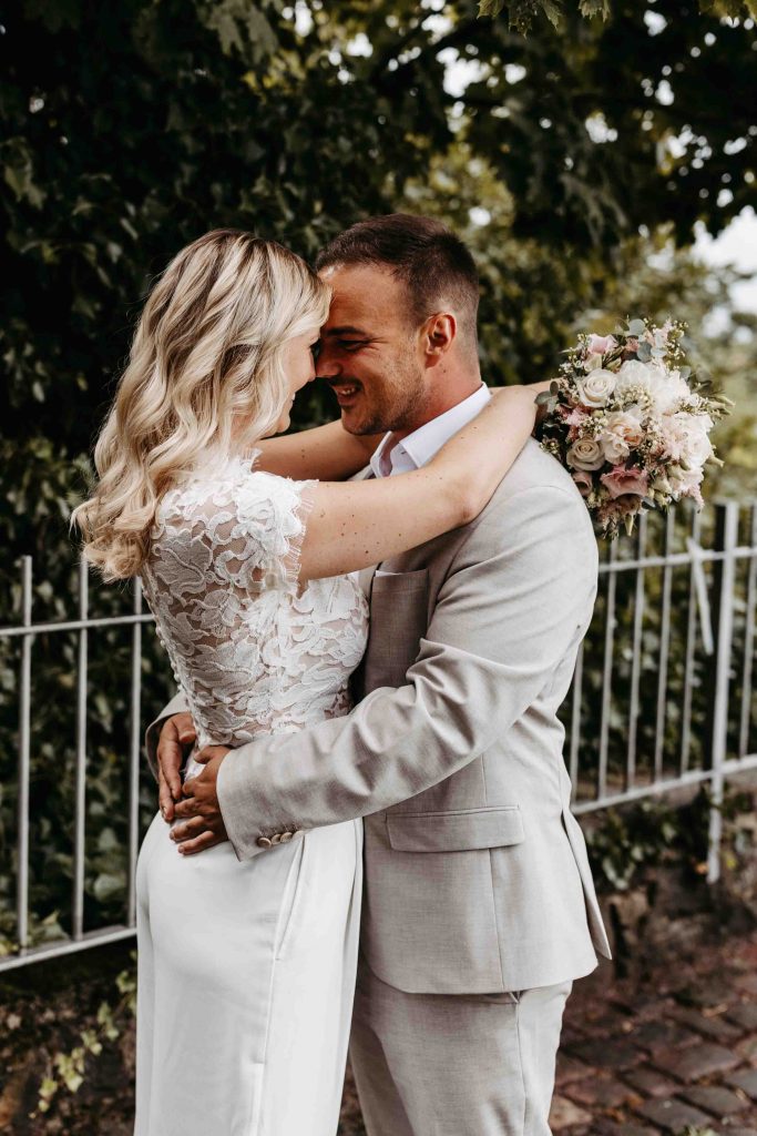 Das Brautpaar lächelt sich an. Sie stehen sich gegenüber - Stirn an Stirn.