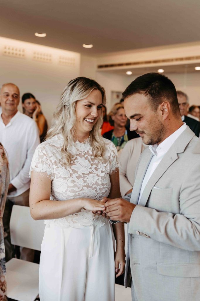 Ringtausch bei der standesamtlichen Trauung im Trausaal in Karlsruhe-Durlach auf dem Turmberg. Der Bräutigam steckt den Ring an den Finger seiner Braut, schaut dabei auf den Ring. Die Braut lächelt ihn dabei an