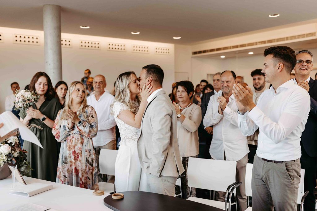 Im Trausaal Durlach auf dem Turmberg. Der erste Kuss nach dem JA. Die Gesellschaft klatscht und das Brautpaar küsst sich innig